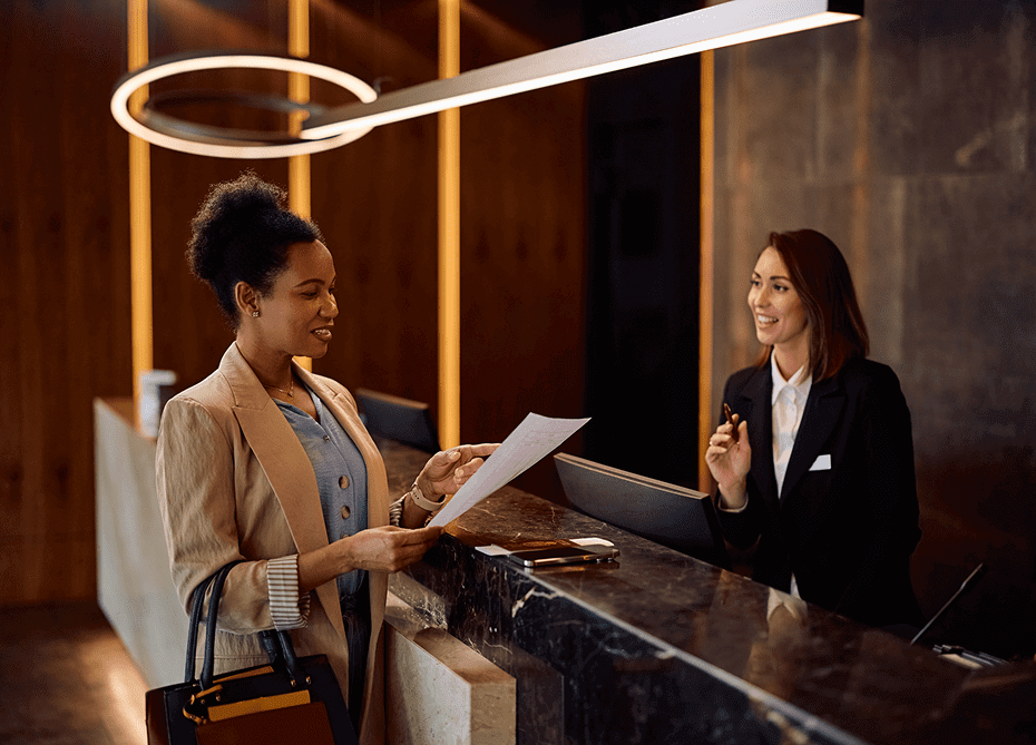 Woman checking in at hotel reception desk.